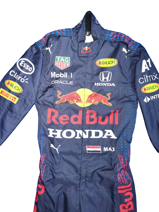A navy Red Bull Racing team racing suit with sponsor logos including Honda, Red Bull, TAG Heuer, Esso, Mobil 1, Oracle, Puma, and Michelin, laid flat on a crinkled blue background.