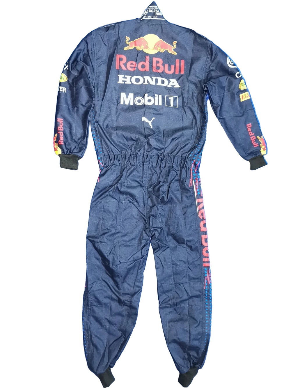A dark navy Red Bull Racing one-piece jumpsuit with sponsor logos including Red Bull, Honda, Mobil 1, Puma, and Castore, laid flat on a crinkled blue background.