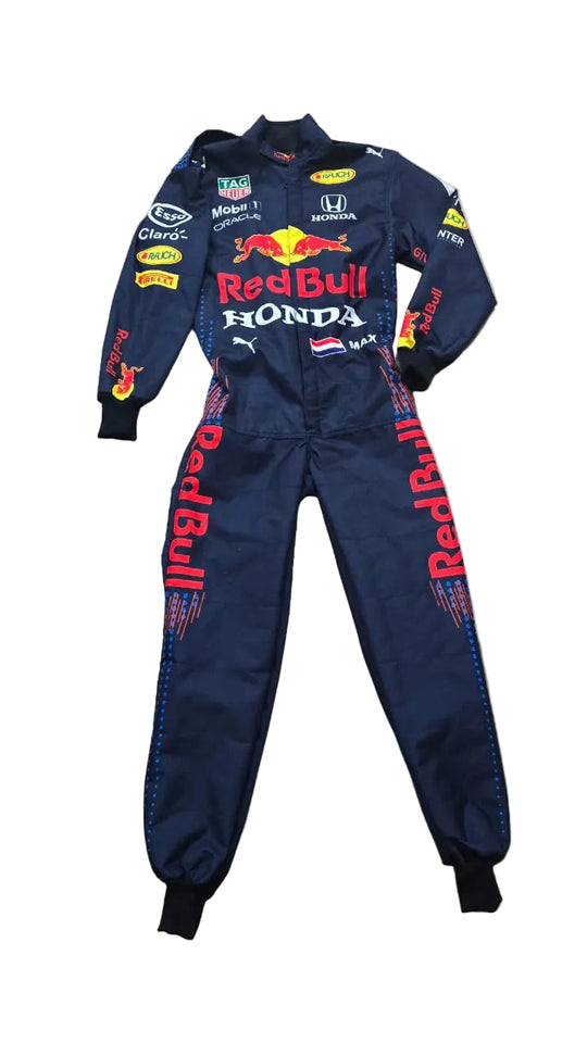 A navy Red Bull Racing Honda team jumpsuit laid flat on a beige stone floor. The suit features multiple sponsor logos including Red Bull, Honda, Puma, Mobil 1, and TAG Heuer, with 'Red Bull' printed in red down the legs.