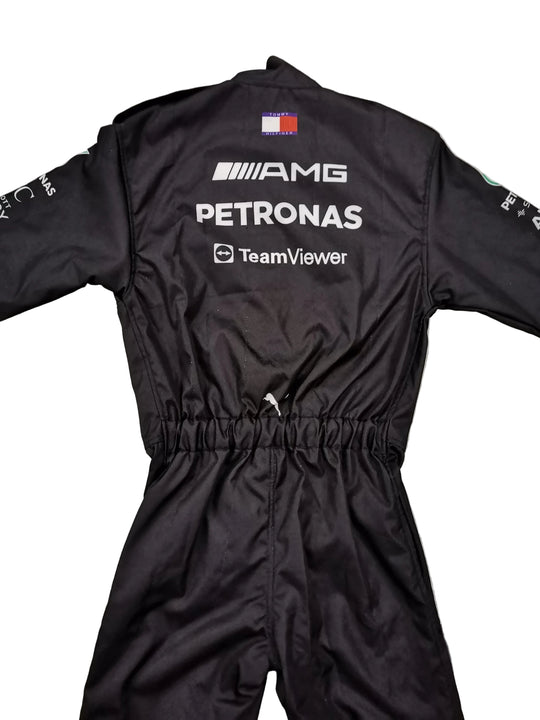 Black Mercedes-AMG Petronas racing suit shown from the back, laid flat on a gray marble-patterned floor. The suit features white sponsor logos including AMG, Petronas, and TeamViewer, along with a small French flag patch near the collar.