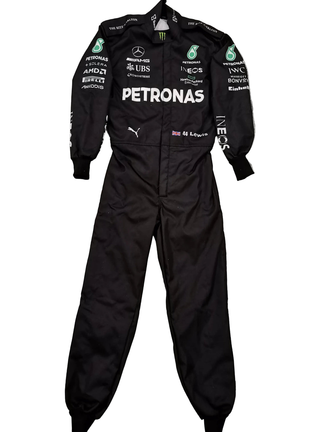 A black Mercedes Petronas racing one-piece suit with various sponsor logos, laid flat on a gray marble-patterned tile floor.