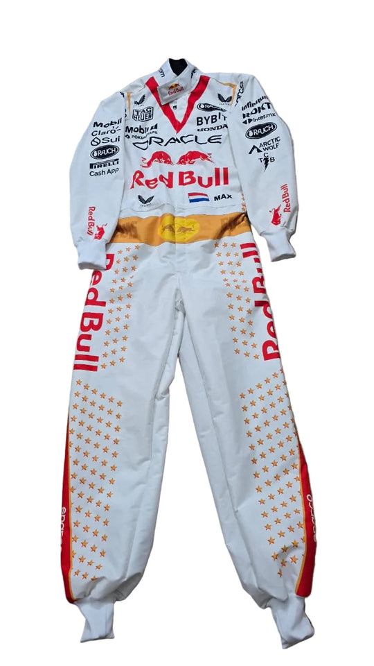 A white Oracle Red Bull Racing long-sleeve racing suit with sponsor logos and orange star patterns on the legs, laid flat on a beige stone floor.