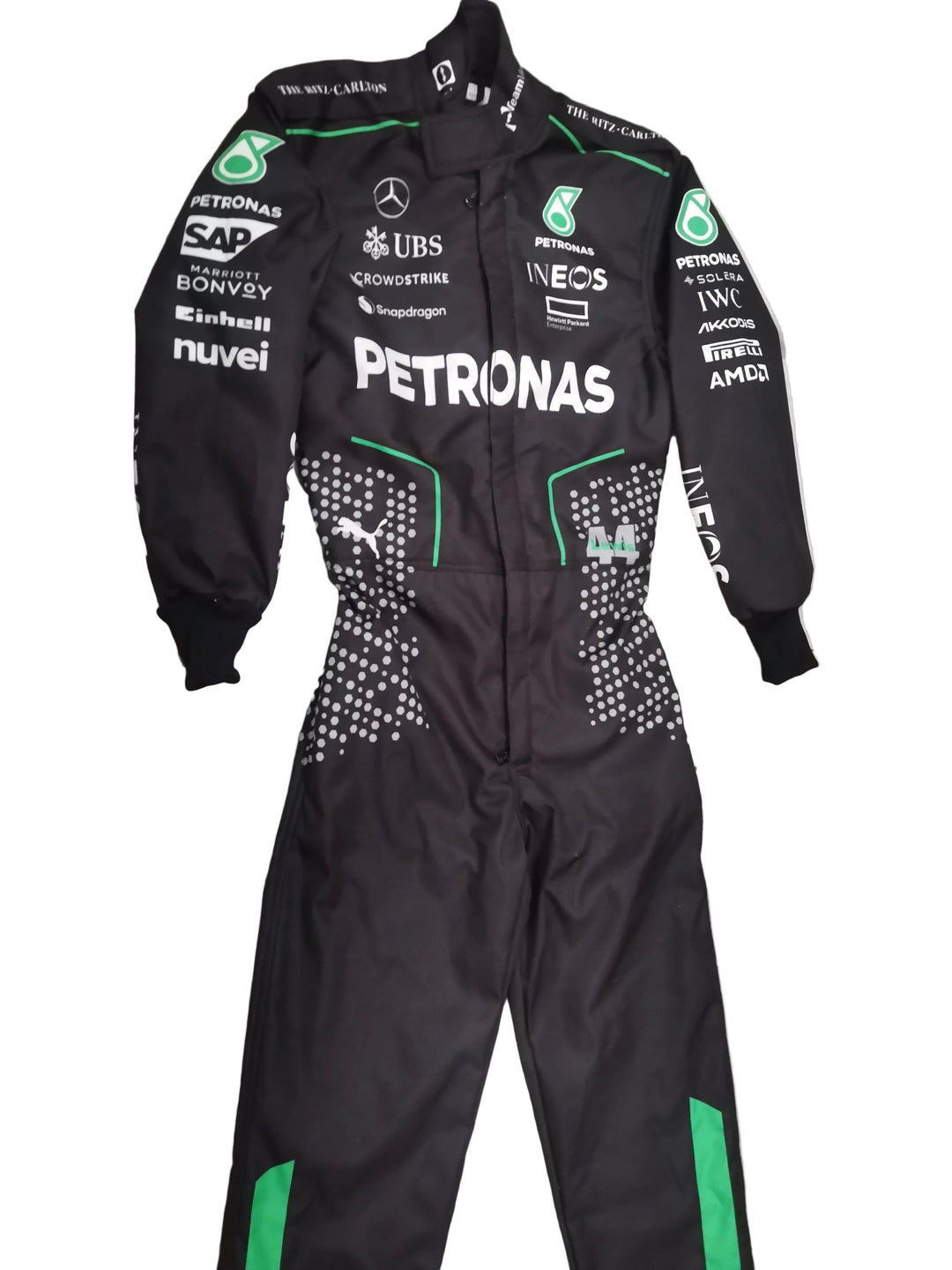 A black Mercedes Petronas Formula 1 racing one-piece suit with green accents and various sponsor logos, laid flat on a gray marble-patterned tile floor.