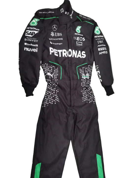 A black Mercedes Petronas Formula 1 racing one-piece suit with green accents and various sponsor logos, laid flat on a gray marble-patterned tile floor.