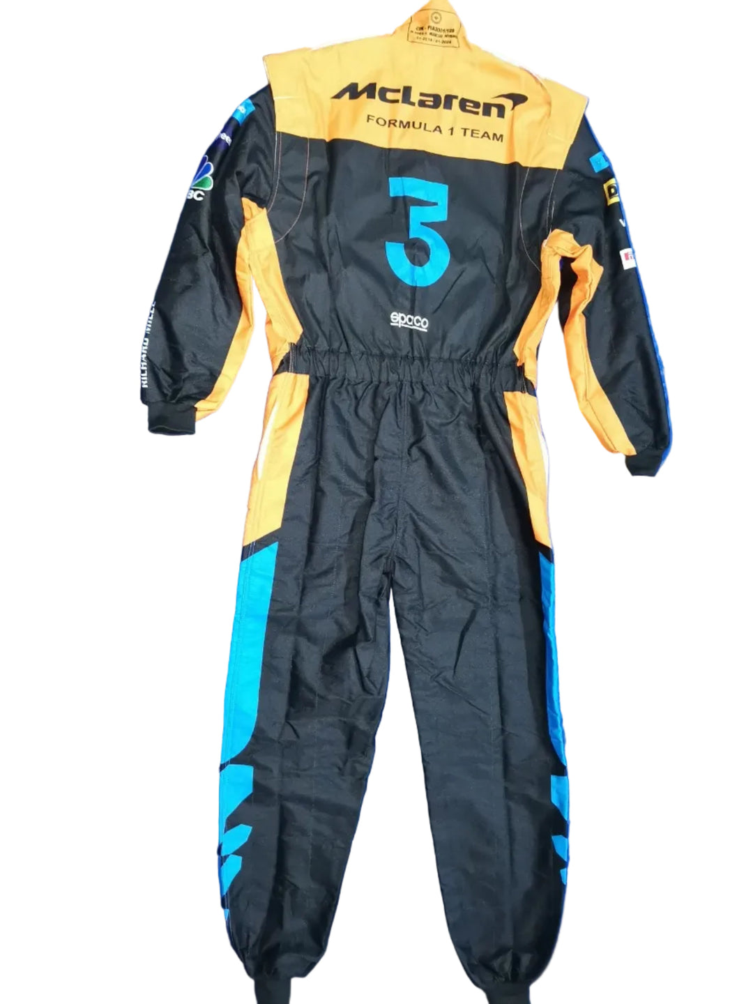 A black and orange McLaren Formula 1 team racing suit with the number 5, laid flat on a crumpled blue tarp. Bare feet are visible at the bottom edge.