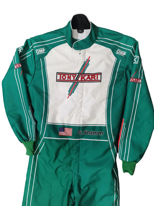 A green and white Tony Karl / G. Stamm racing suit laid flat on a black background.