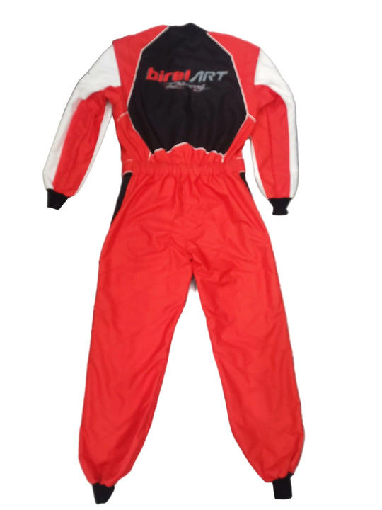 A red, white, and black one-piece racing suit laid flat on a gray marble floor. The suit features a black and red chest panel with 'biretART Racing' printed in white and red, white sleeves, and a red body.