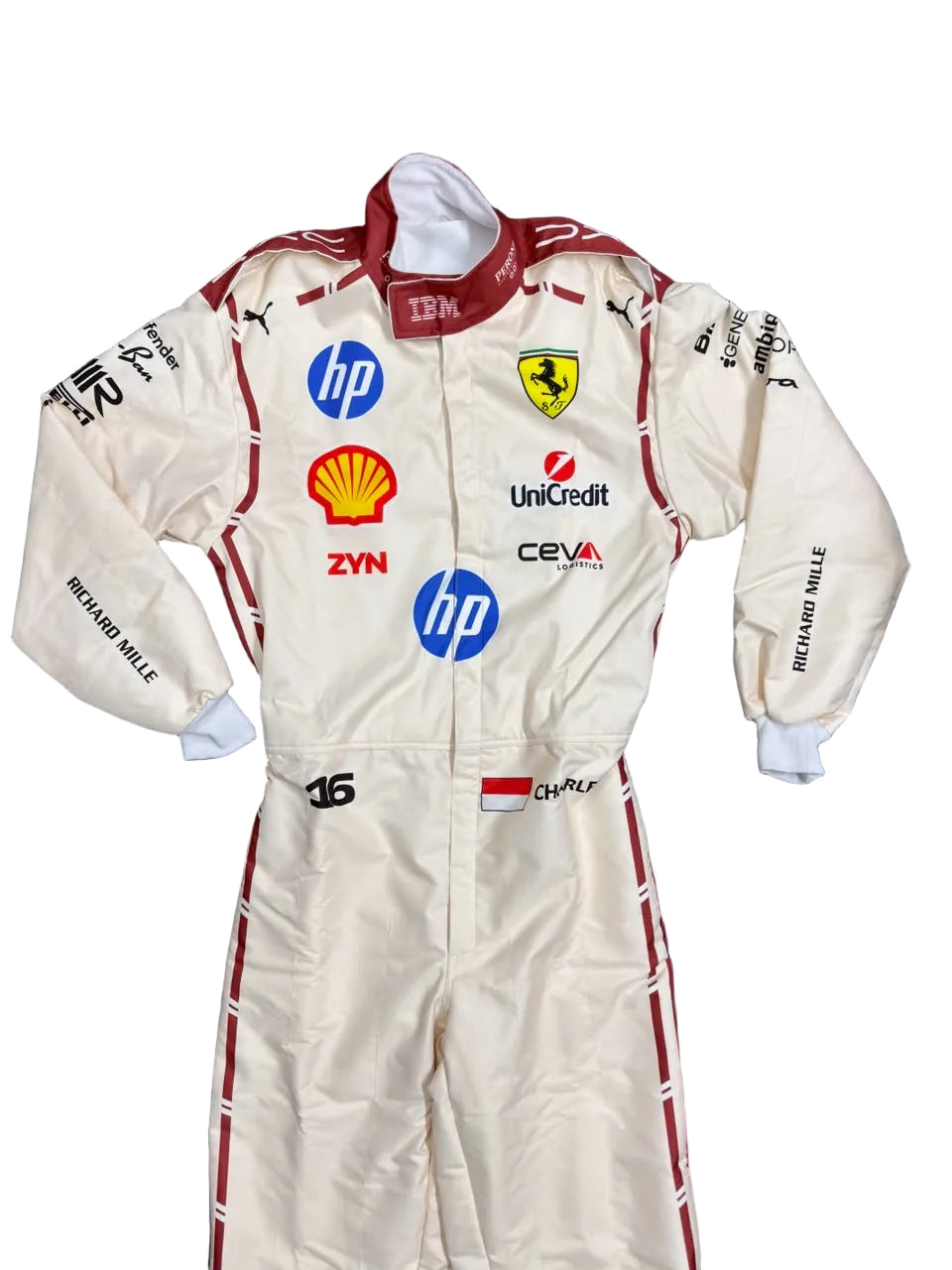 A cream-colored Scuderia Ferrari racing suit by Richard Mille, featuring multiple sponsor logos including HP, Shell, and Unipred, laid flat on a dark blue blanket.