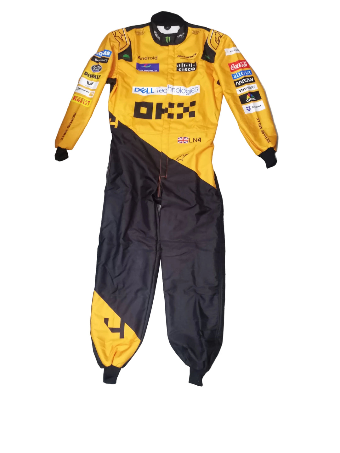 A yellow and black racing suit with multiple sponsor logos, laid flat on a gray marble-patterned floor. The suit features prominent 'Dell' logo on the chest and various other racing team and brand patches.