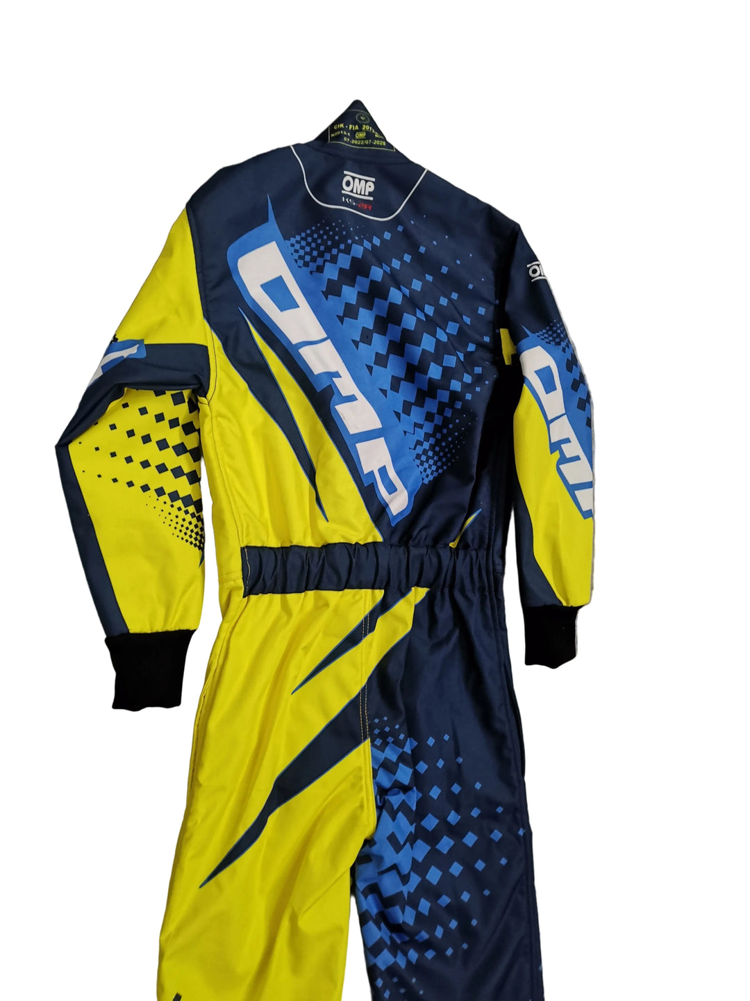 A full-body racing suit with a bold yellow and navy blue color-blocked design, featuring geometric patterns and the word 'DAMO' printed prominently on the back, hanging against a gray tiled wall.