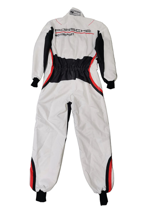 A white Porsche Motorsport one-piece racing suit with black and red accents, laid flat on a gray and black marble-patterned tile floor. The suit features the 'PORSCHE Motorsport' logo on the chest.