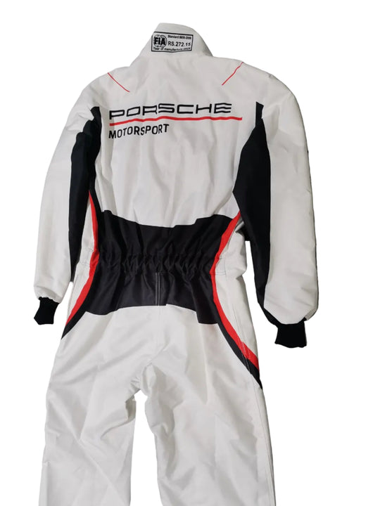 A white one-piece racing suit with black and red accents, featuring 'PORSCHE MOTORSPORT' printed vertically on the back, laid flat on a gray marble-patterned floor.