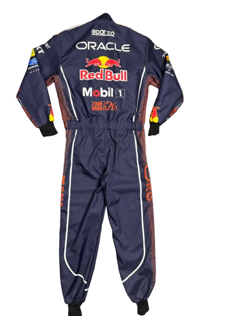 A navy blue Oracle Red Bull Racing one-piece racing suit with sponsor logos, laid flat on a gray tiled floor. The suit features white and orange graphics, with the Red Bull logo and sponsor names including Mobil 1, 2GO, and Spark.