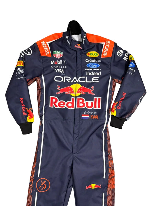A Red Bull Racing team one-piece racing suit laid flat on a gray tiled floor. The suit is navy blue with orange and white accents, featuring prominent sponsor logos including Oracle, Red Bull, Castore, Mobil 1, and Ford.